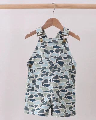 Camouflage-patterned overalls hanging on a wooden hanger against a white background
