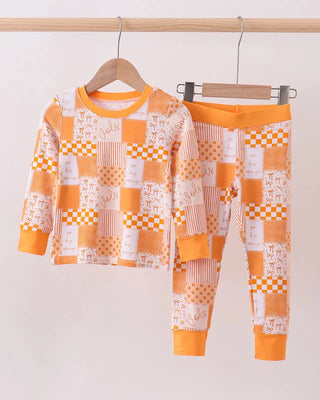 Children's pajama set with orange and white checkered pattern hanging on a rack.
