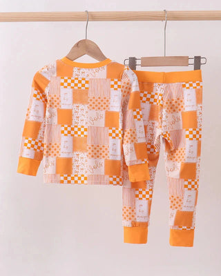 Children's pajama set with orange and white checkered pattern on a hanger against a white background