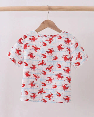 Children's t-shirt with red crab pattern on a wooden hanger against a beige background