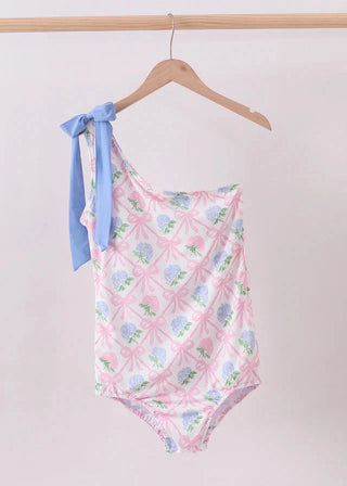 One-piece swimsuit with floral pattern and blue tie on a hanger against a light background
