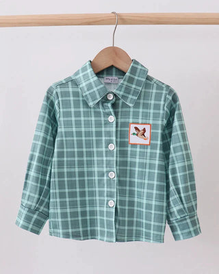 Green plaid shirt with a duck patch on a hanger against a white background