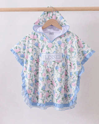 Floral patterned poncho with 'blessed' text on a wooden hanger against a white background