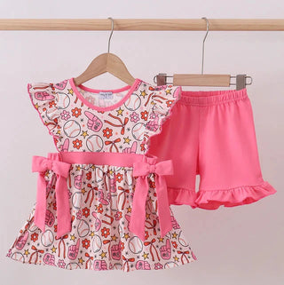 Children's outfit with a baseball patterned top and pink shorts on a hanger against a white background