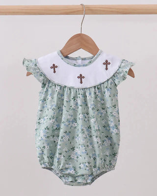 Floral baby romper with cross details on a hanger against a plain background