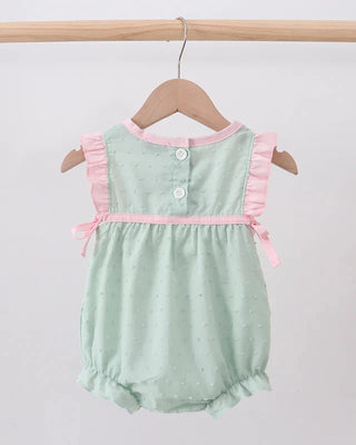 Green baby romper with pink trim on a wooden hanger against a white background
