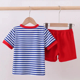 Children's striped shirt and red shorts on hangers against a light background