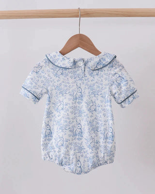 Baby romper with floral pattern on a wooden hanger against a white background