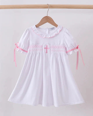 White dress with pink accents on a hanger against a plain background