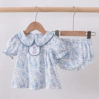 Baby’s floral outfit with a collar on a wooden hanger against a light gray background