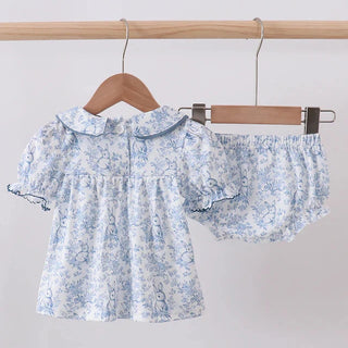 Baby’s floral outfit with top and shorts on a hanger against a light gray background