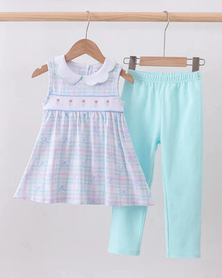 Children's dress and leggings set on hangers against a white background
