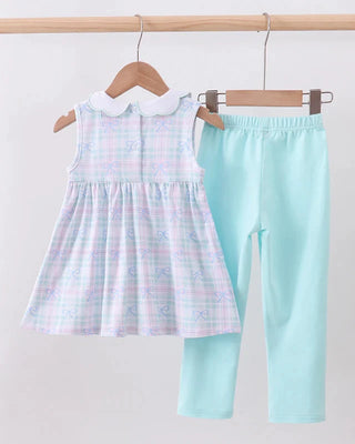 Pastel checkered dress and light blue pants hanging on a rack against a white background