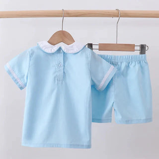 Light blue children's shirt and shorts set on hangers against a light gray background