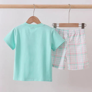 Children's mint green shirt and checkered shorts on hangers against a light gray background