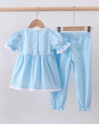 Light blue children's outfit with top and pants on hangers against a white background