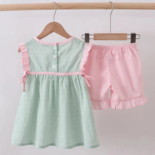 Children's green top with pink trim and matching shorts on a hanger against a white background