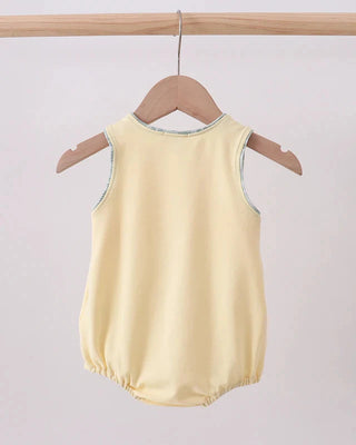 Yellow baby romper on a wooden hanger against a light gray background