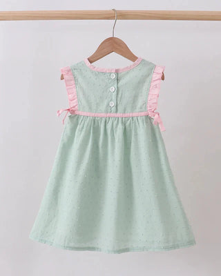 Green dress with pink trim on a wooden hanger against a white background