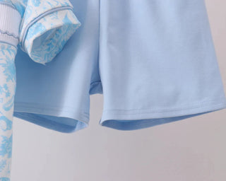 Light blue children's outfit with floral pattern on a neutral background