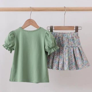 Green top and floral skirt on hangers against a white background