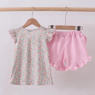 Floral top and pink shorts on hangers against a light gray background