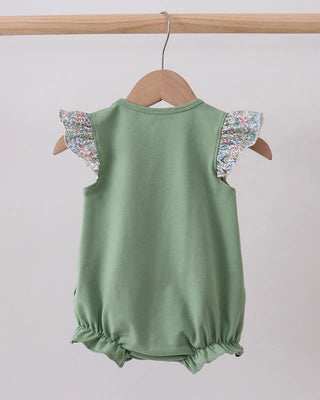 Green baby romper with floral sleeves on a wooden hanger against a white background