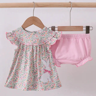 Floral top with ruffled collar and pink bloomers on a wooden hanger against a white background