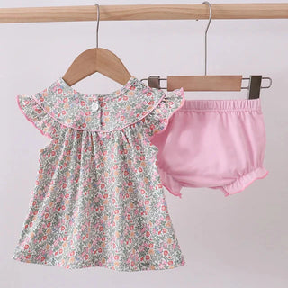 Baby dress with floral pattern and pink bloomers on a hanger against a light gray background