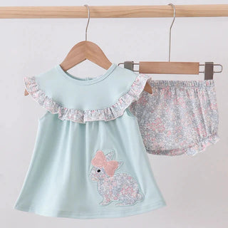 Children's outfit with a light blue top and floral shorts on hangers against a white background