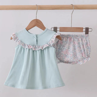 Children's light blue top and floral bloomers on hangers against a plain background