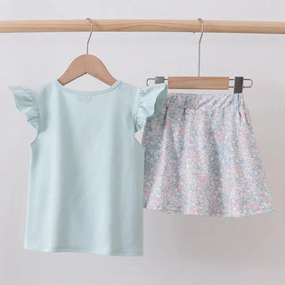 Children's light blue top and floral shorts on hangers against a white background