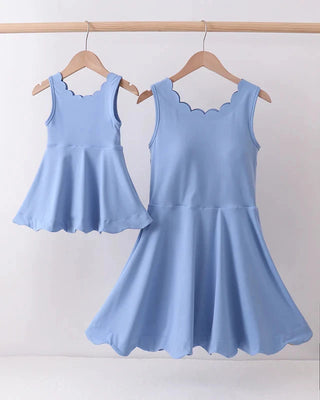 Two light blue dresses hanging on wooden hangers against a white background