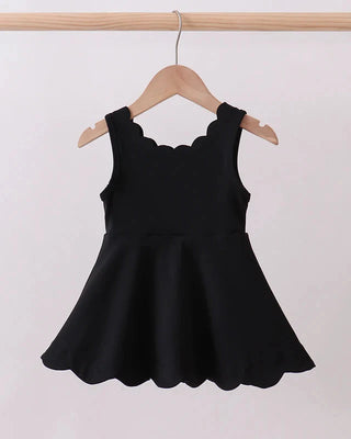 Black dress on a hanger against a plain background