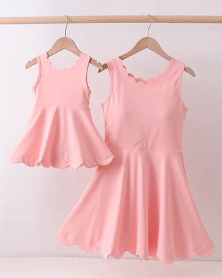 Two pink sleeveless dresses hanging on a rack against a white background