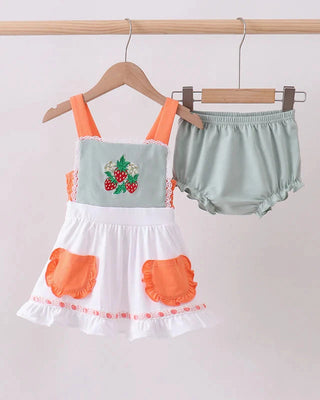 Children's set with strawberry design and bloomers on hangers against a plain background