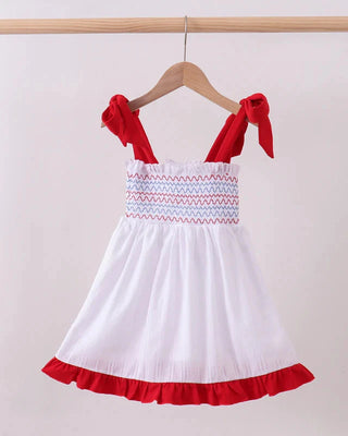 White dress with red accents on a hanger against a white background