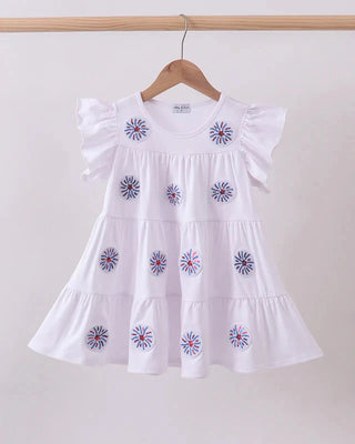 White dress with firework sequin embroidery on a hanger against a plain background