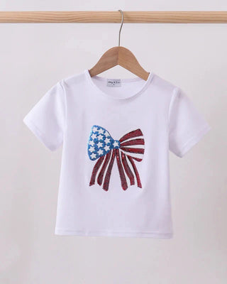 White t-shirt with a bow design featuring the American flag on a wooden hanger against a light background.