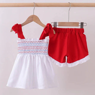 Red and white children's outfit on hangers against a plain background
