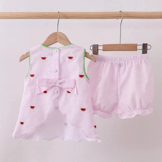 Pink children's outfit with watermelon patterns on a wooden hanger against a white background