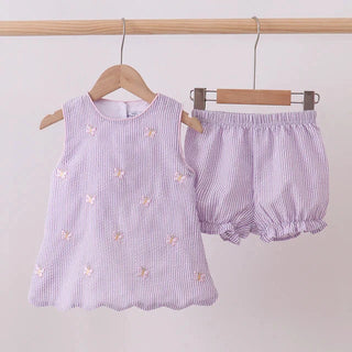 Purple striped baby outfit with top and bloomers on hangers against a light background