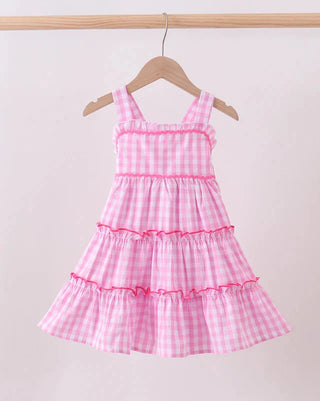 Pink checkered dress on a hanger against a white background
