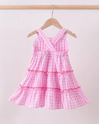 Pink checkered dress on a hanger against a light background