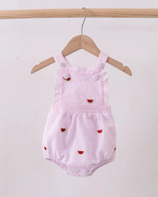 Pink baby romper with watermelon patterns on a wooden hanger against a white background