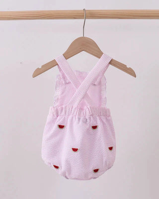 Pink baby romper with watermelon accents on a wooden hanger against a white background