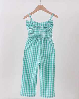 Green and white checkered jumpsuit hanging on a wooden hanger against a white background