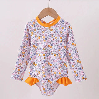 Floral-patterned children's swimsuit with orange trim on a wooden hanger against a light background
