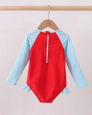Red and light blue swimsuit on a hanger against a plain background
