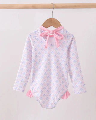 Swimsuit with floral pattern and pink accents on a hanger against a light background